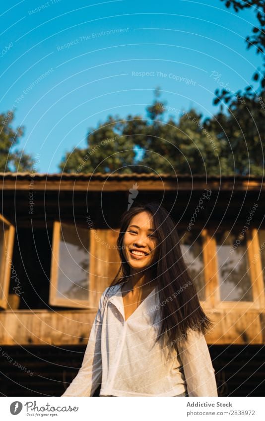 Hübsche Frau, die in der Nähe des Hauses posiert. hübsch asiatisch Jugendliche Behaarung brünett Freude Holz Sonnenstrahlen schön Porträt attraktiv