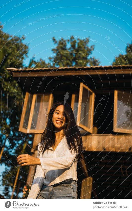 Hübsche Frau, die in der Nähe des Hauses posiert. hübsch asiatisch Jugendliche Behaarung Schütteln brünett Freude Holz Sonnenstrahlen schön Porträt attraktiv