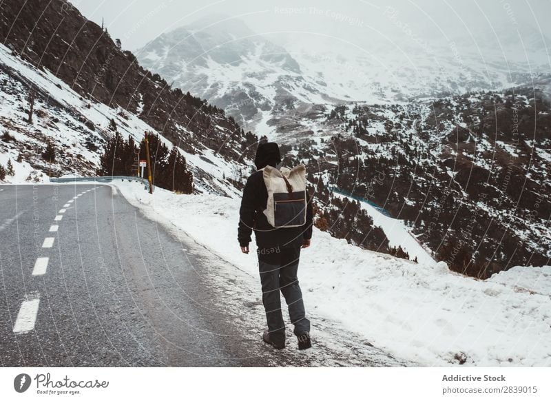 Mann, der auf einer verschneiten Straße geht. Winter Hügel Berge u. Gebirge Schnee Landschaft Natur weiß Eis Jahreszeiten kalt Ferien & Urlaub & Reisen Weg Wald
