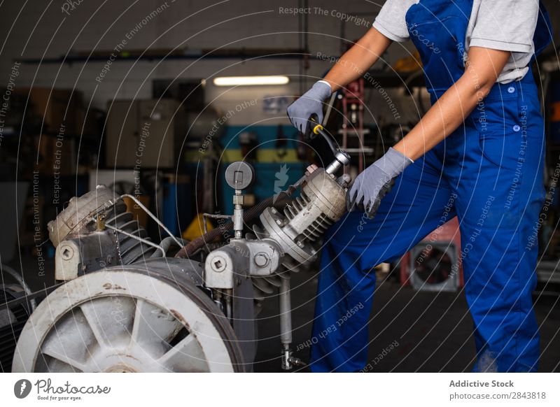 Mechanikerin, die einen Kompressormotor mit einem Schraubenschlüssel befestigt. Automechaniker Frau Porträt Reparatur Mitarbeiter industriell Lokomotive