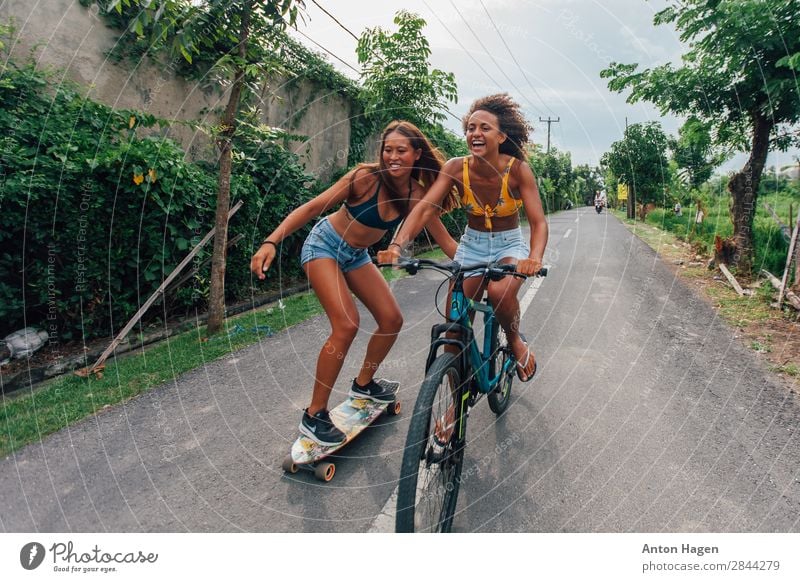 Zwei junge Frauen, die Fahrrad fahren und Skateboard fahren. Lifestyle Sport Fitness Sport-Training Mensch feminin Junge Frau Jugendliche 2 18-30 Jahre