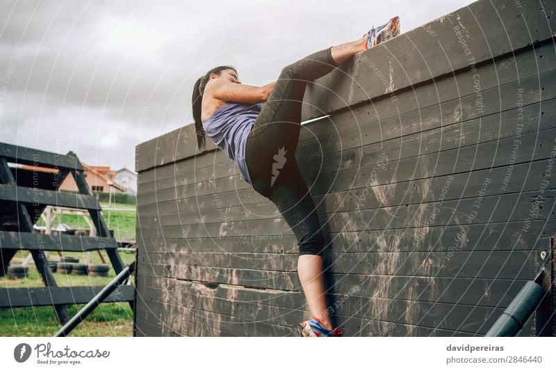 Weibliche Teilnehmerin im Hindernisparcours an der Kletterwand Lifestyle Sport Klettern Bergsteigen Mensch Frau Erwachsene Turnschuh authentisch stark