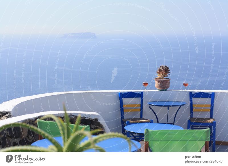 Santorini. Blick aufs Meer von einer Terrasse eines  Restaurants. Blaue stühle, Weingläser, Kaktus. Typisch griechisch Lifestyle Tourismus Bar Cocktailbar