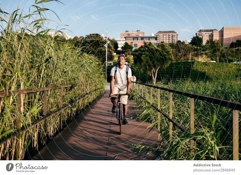Junger Mann fährt Fahrrad auf dem Bürgersteig Straßenbelag Reiten Gras Brücke Geländer Lifestyle Verkehr Stadt Zyklus Großstadt Aktion Gasse Motorradfahren