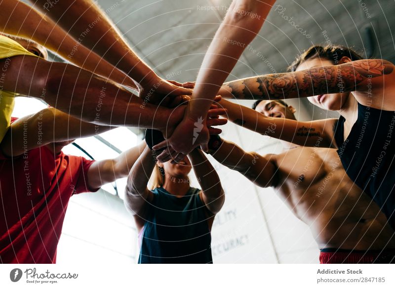 Sportliche Menschen beim Händestapeln Sportler Zusammensein Sporthalle Teamwork Hände stapeln Errungenschaft Einheit abstützen Bodybuilding heiter muskulös