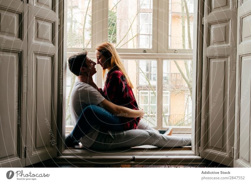Paar küssend auf Fensterbank Liebe umarmend Fensterbrett Zärtlichkeit Küssen Bonden Jugendliche schön Mann Frau Partnerschaft Romantik Zusammensein attraktiv