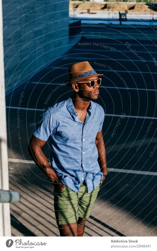 Stilvoller schwarzer Mann, der auf der Straße posiert. Sommer Körperhaltung trendy Stadt Schickimicki Hemd Bekleidung modisch gutaussehend maskulin lässig Hut