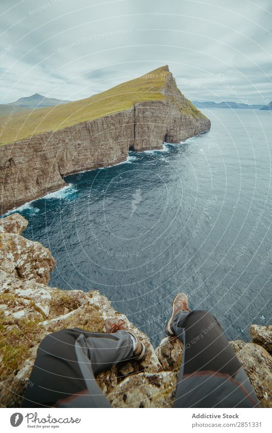 Anonymer Mann auf einer Klippe sitzend Landschaft Höhe Mittelgebirge Meer Felsen dramatisch Freiheit Berge u. Gebirge Panorama (Bildformat) Aussicht Natur