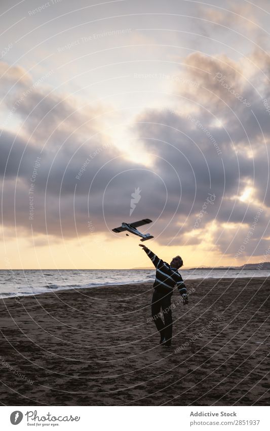 Ein Mann an einem Strand, der das Spielzeugflugzeug wirft. Mensch Flugzeug Spielen werfen Etage Glück Freude Lifestyle träumen kindisch Abend Küste Meer Wasser