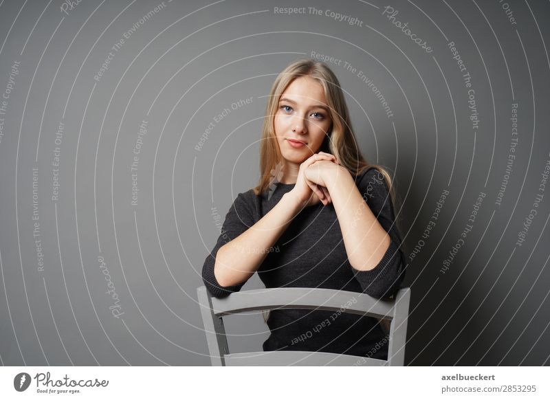 junge Frau sitzt rittlings auf Stuhl Mensch feminin Junge Frau Jugendliche Erwachsene 1 13-18 Jahre 18-30 Jahre blond langhaarig sitzen schön grau Farbfoto