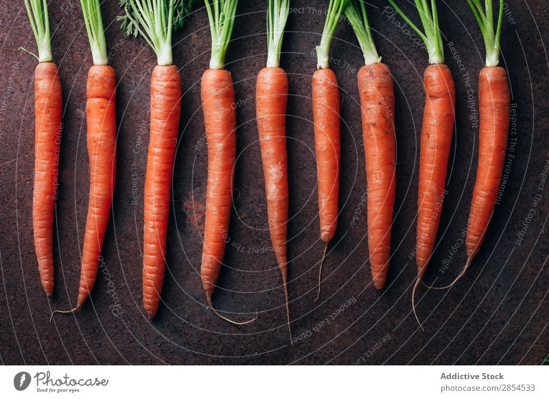 Ein Haufen frischer Karotten in dunklem metallischem Hintergrund. Hintergrundbild Möhre mehrfarbig dunkel Lebensmittel Ernte Gesundheit Metall Ernährung Orange