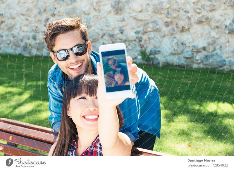 Junges glückliches Paar mit Smartphone im Park asiatisch schön Freund lässig Solarzelle Handy Chinese Mitteilung Verbindung Textfreiraum Frau Freundschaft