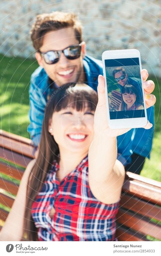 Junges glückliches Paar mit Smartphone im Park sitzend asiatisch schön Freund lässig Solarzelle Handy Chinese Mitteilung Verbindung Textfreiraum Frau