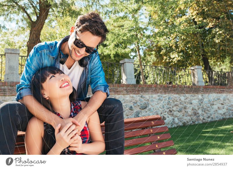 Junges glückliches Paar mit Smartphone im Park sitzend asiatisch schön Freund lässig Solarzelle Handy Chinese Mitteilung Verbindung Textfreiraum Frau