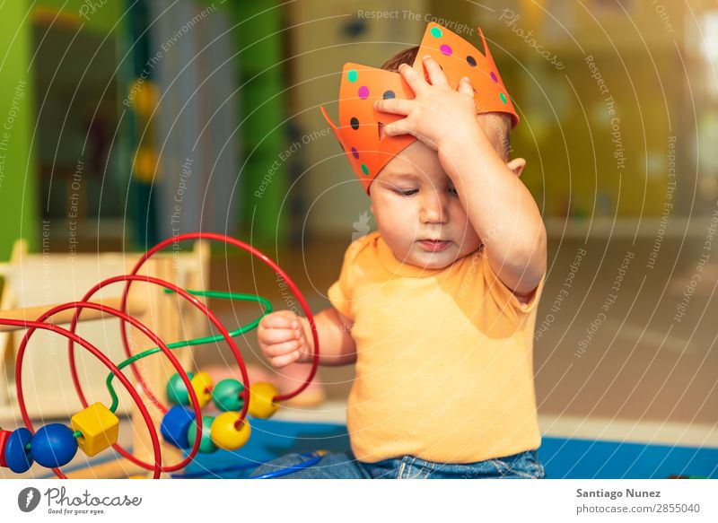 Frohes Baby beim Spielen mit Spielzeugblöcken. Kinderbetreuung Kindergarten Schule Krone König beißen Kleinkind Junge klein Glück Fürsorge Etage Porträt
