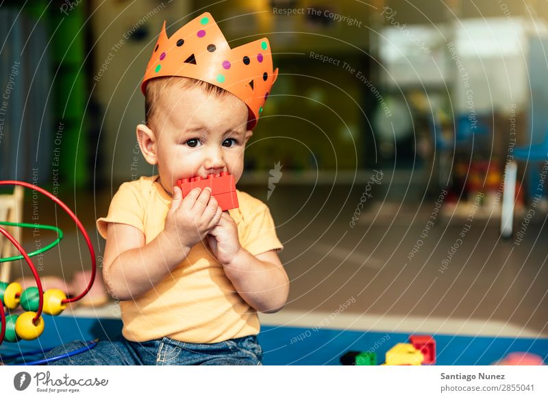 Frohes Baby beim Spielen mit Spielzeugblöcken. Kinderbetreuung Kindergarten Schule Krone König beißen Kleinkind Junge klein Glück Fürsorge Etage Porträt