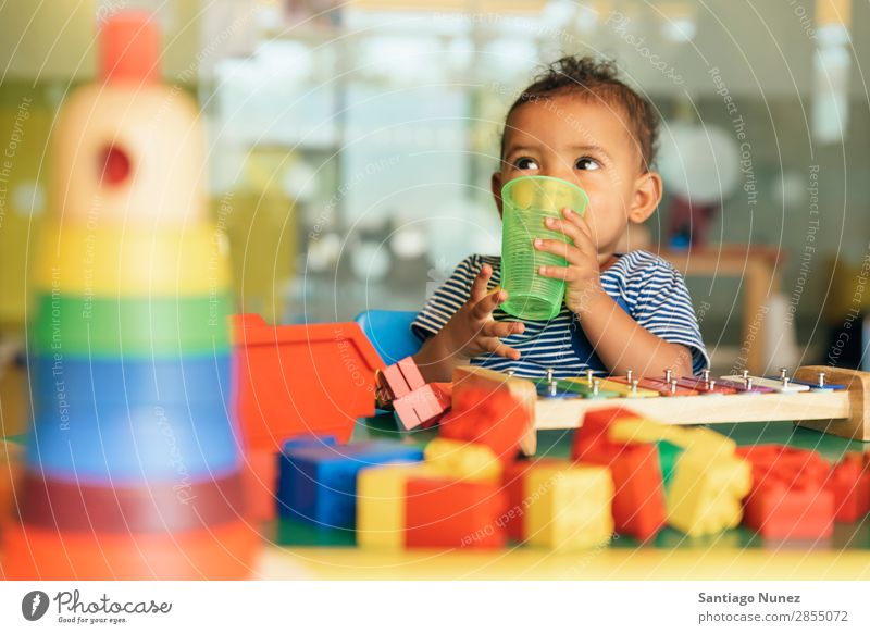 Frohes Baby, das Wasser trinkt und spielt. Spielen Kinderbetreuung Kindergarten Schule Spielzeug Kleinkind Mädchen klein Blöcke Glück Fürsorge Etage niedlich