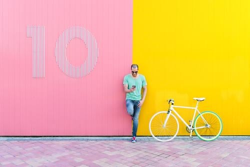 Gutaussehender junger Mann mit Handy und festem Fahrrad. Mobile Fixie Telefon Schickimicki Lifestyle stehen Fahrradfahren Großstadt Solarzelle Stadt Mensch