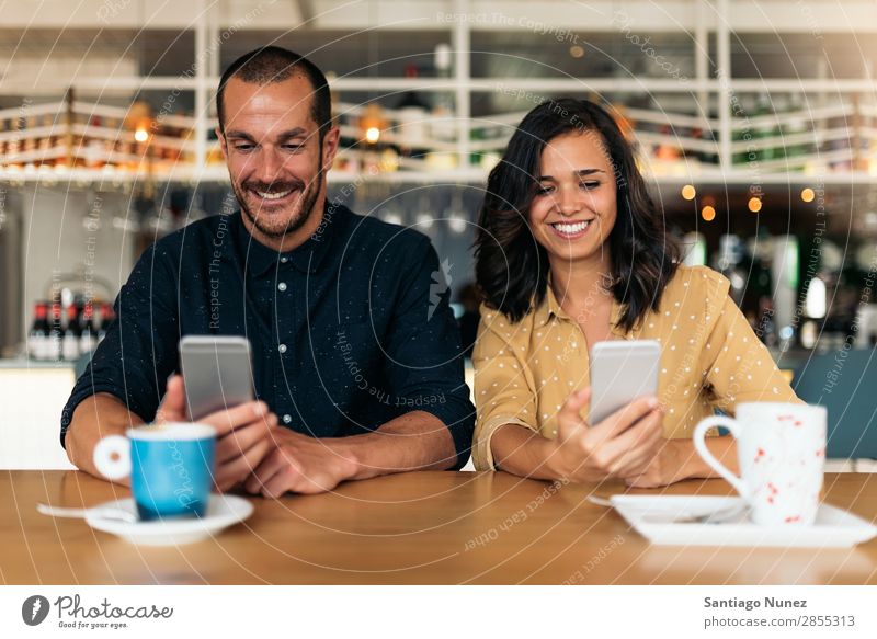 Glückliche Freunde, die das Handy benutzen. Frau Café Kaffee Mann Telefon Paar Mobile Lächeln schön Lifestyle Datteln Freundschaft Liebe Freude Bar Tisch