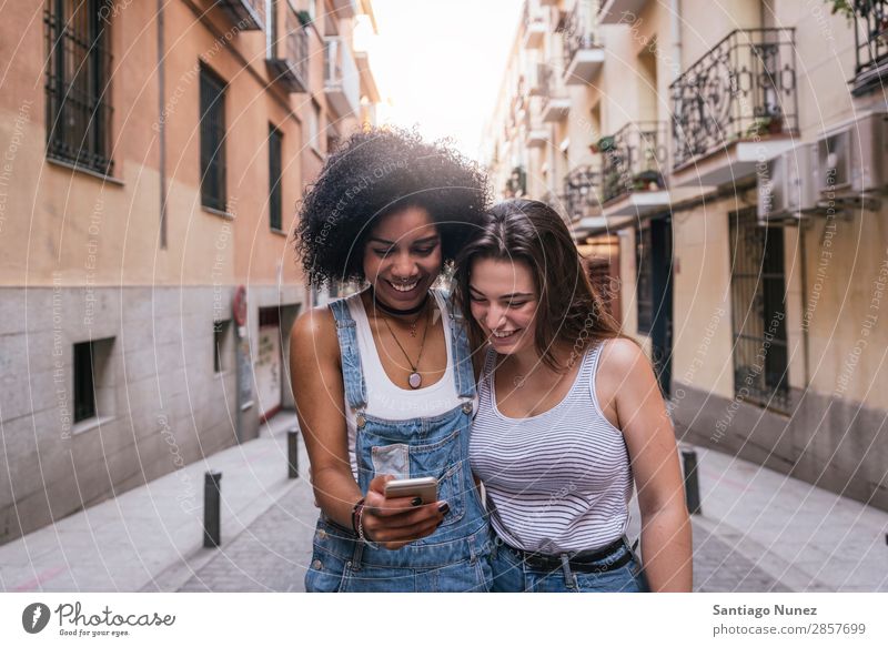 Schöne Frauen, die ein Handy auf der Straße benutzen. Freundschaft Afro-Look Jugendliche Glück Sommer Mensch Freude Mobile PDA Telefon Solarzelle benutzend