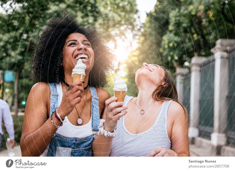 Schöne Frauen essen ein Eis auf der Straße. Freundschaft Jugendliche Afro-Look Speiseeis Kornett Verkostung Essen Creme Glück Sommer Porträt Mensch Freude