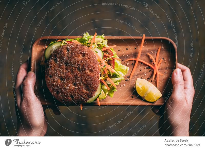 Frau hält ein Tablett mit einem vegetarischen Sandwich. Avocado Biografie Brot Brötchen Burger Möhre Gurke lecker deluxe Diät Öko ökologisch Lebensmittel frisch