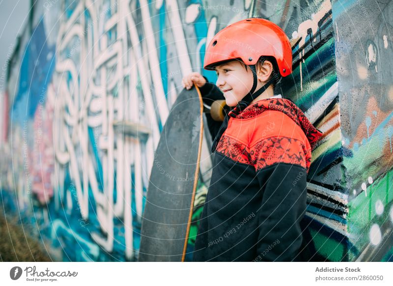 Kind mit langem Brett Holzplatte Junge Kaukasier Gerichtsgebäude Graffiti Helm lernen Longboard Außenaufnahme Park Spielen Schutz Schlittschuhe Skateboard