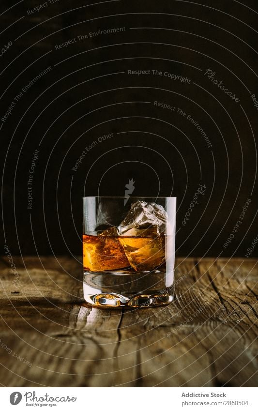 Ein Glas Whiskey auf einem Holztisch Alkohol Amber Hintergrundbild Bar Barmann Barkeeper Getränk Flasche Bourbon Weinbrand Cognac dunkel trinken gold Eis