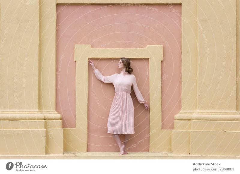 Frau in rosa Kleid, die an der Wand posiert. hübsch Jugendliche altehrwürdig Körperhaltung stehen sitzen schön attraktiv Mensch Beautyfotografie Erwachsene Stil