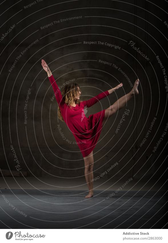 Junge Frau mit hochgezogenem Bein in der Dunkelheit Balletttänzer Ballerina Tanzen Kleid Beine Hand erhöht Leistung Raum rot elegant dunkel Kunst Pose Show