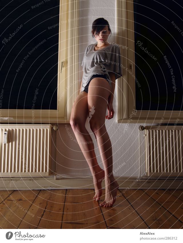 Kraft und Anmut und 2 Heizkörper Heizung Wohnzimmer Holzfußboden Fenster Junge Frau Jugendliche Kopf Beine Fuß 18-30 Jahre Erwachsene Barfuß schwarzhaarig