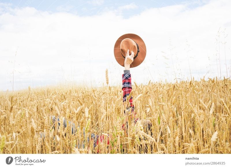 Hand hält einen Cowboyhut über einem Weizenfeld. Bioprodukte Lifestyle Stil Design Freude Glück schön Wellness Leben Wohlgefühl Zufriedenheit Erholung Freiheit