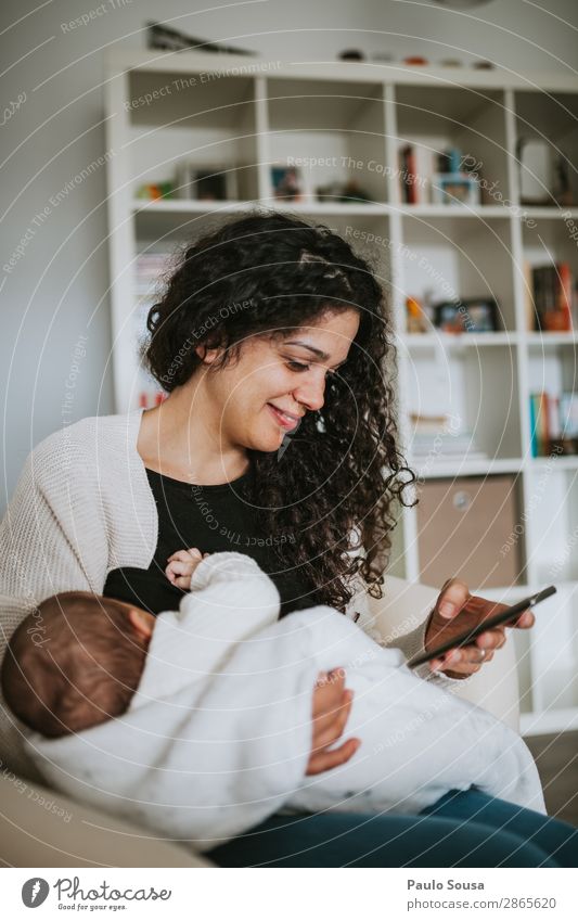 Mutter stillen Baby beim Spielen mit dem Smartphone Lifestyle Handy Mensch Kind Kleinkind Junge Frau Jugendliche Erwachsene 2 0-12 Monate 18-30 Jahre Fressen