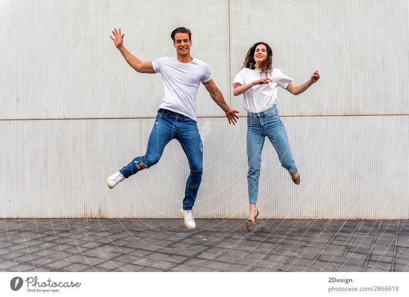 Ein glückliches verliebtes Paar, das gegen eine graue Wand springt. Lifestyle Freude Glück Freizeit & Hobby Haus Mensch maskulin feminin Junge Frau Jugendliche