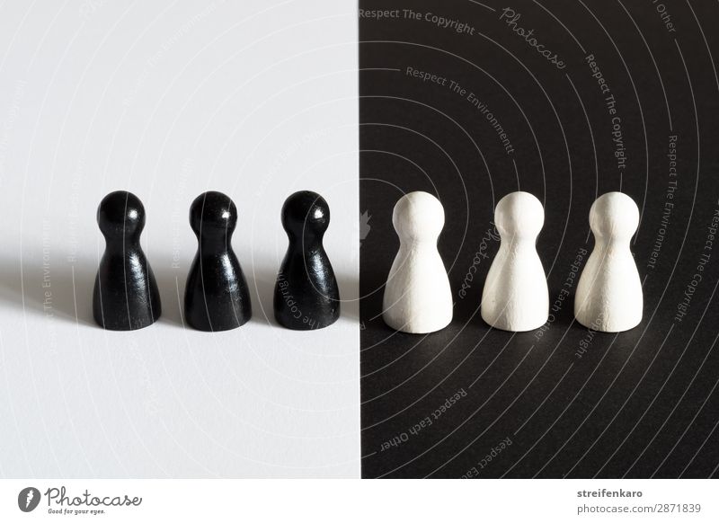 Schwarze Spielfiguren auf weißem Untergrund stehen weißen Spielfiguren auf schwarzem Untergrund gegenüber Menschengruppe Spielzeug Holz beobachten Akzeptanz