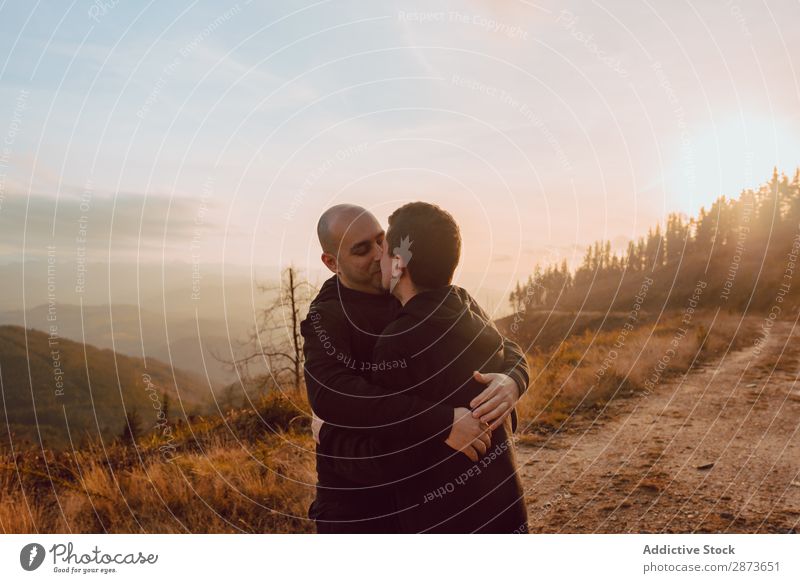Männer, die sich im Wald umarmen und küssen. Homosexualität Paar Park Küssen Liebe Händchenhalten Wege & Pfade Schönes Wetter geschlossene Augen Sonne Natur