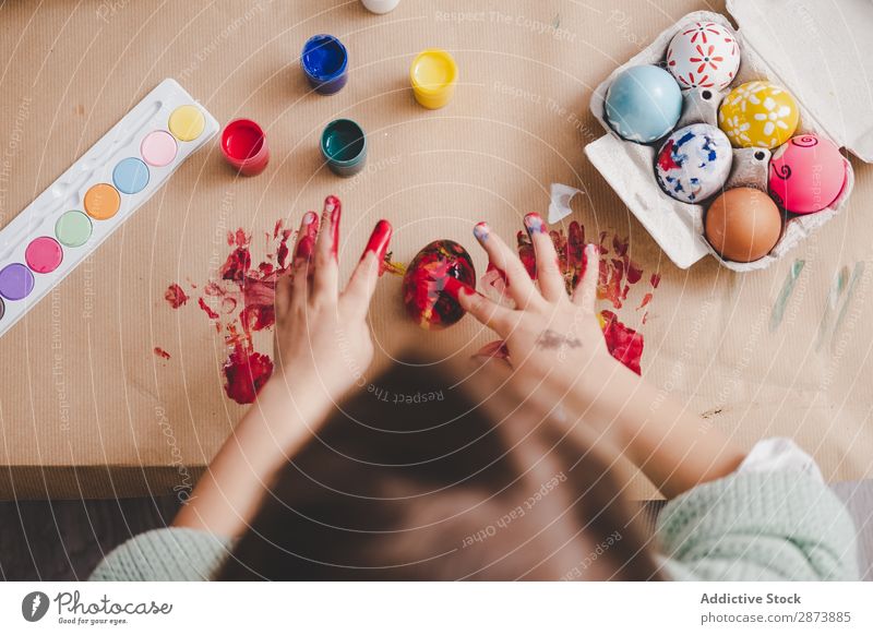 Kind mit schmutzigen Händen in der Nähe von Hühnereiern und Farben am Tisch. Hand Ostern Ei dreckig malen Handfläche Hähnchen Container Frühling Kulisse
