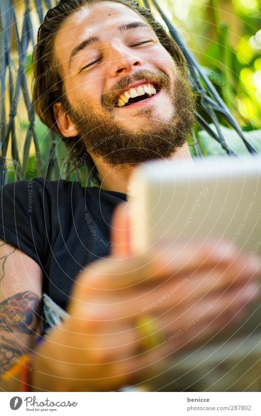 am Tablet Mann Mensch Junger Mann Bart Tablet Computer Touchpad berühren Tippen lachen Freude Natur Lächeln Internet Tattoo tätowiert Vollbart Hängematte liegen