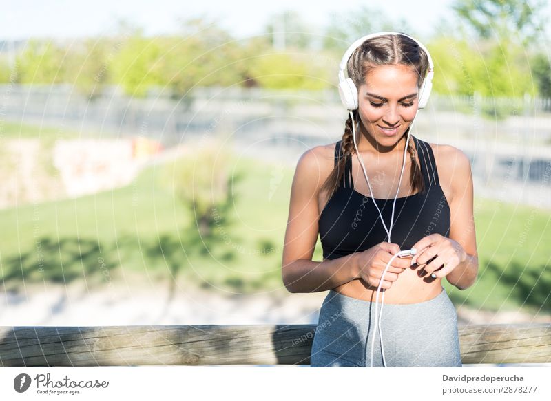 Nahaufnahme eines Porträts einer Frau, die Sport treibt, sich im Freien ausruht, lächelt und Musik hört Joggen Sportlerin laufen rennen Fitness strecken Übung
