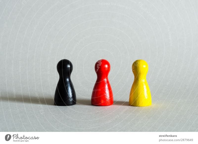 Drei Spielfiguren in schwarz, rot, gelb stehen in einer Reihe Spielzeug Holz Zeichen Fahne gold Einigkeit Gesellschaft (Soziologie) Politik & Staat Regierung