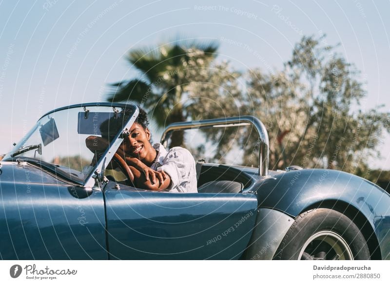 Schwarze Frau fährt ein Oldtimer-Cabriolet. PKW fahren Glück urwüchsig Straße schwarz Reichtum Blick in die Kamera Profil heiter Lächeln klassisch 60's schön