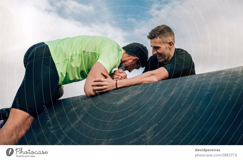 Männlicher Teilnehmer im Hindernislauf, der von einem Teamkollegen unterstützt wird Lifestyle Freude Sport Klettern Bergsteigen Mensch Mann Erwachsene Hand