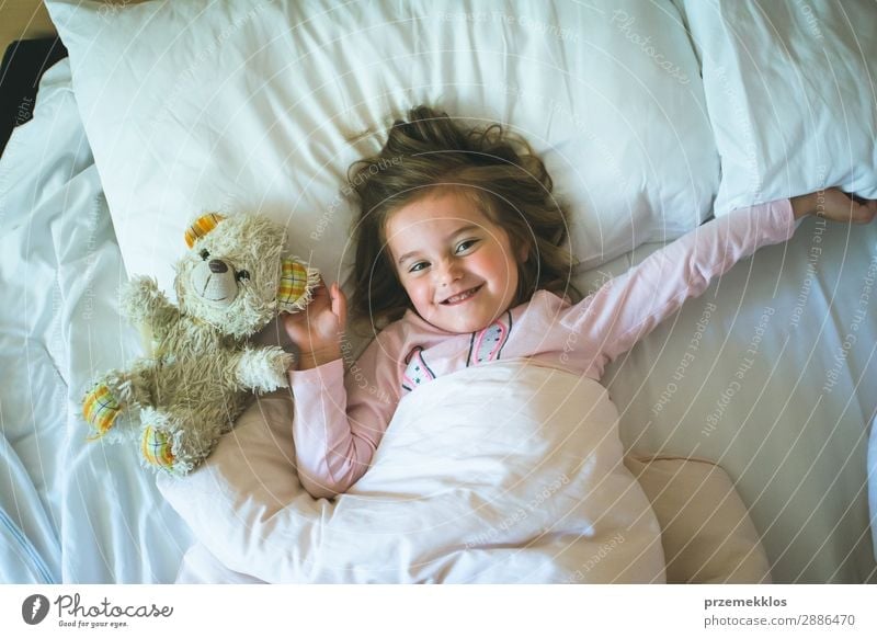 Kleines Mädchen liegt in einem Bett mit Teddybär am Morgen. Glücklicher Morgen. Schlafenszeit. Wochenendmorgen schön Spielen Kind Mensch Frau Erwachsene