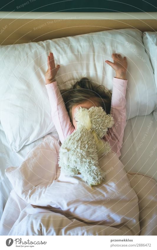 Kleines Mädchen liegt in einem Bett mit Teddybär am Morgen. Glückliche Morgen. Mädchen Kind genießt Morgen im Bett schön Spielen Mensch Frau Erwachsene