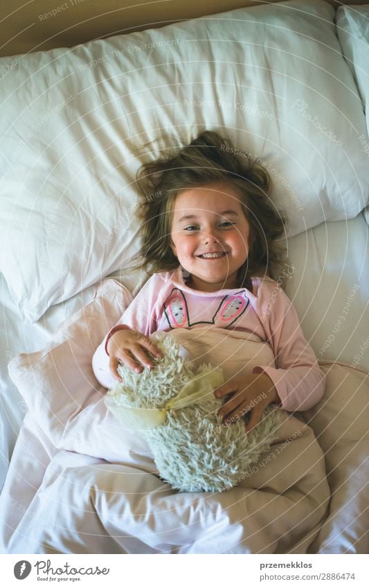 Kleines Mädchen, das morgens in einem Bett mit Teddybär liegt. Glück schön Kind Mensch Frau Erwachsene Spielzeug schlafen Fröhlichkeit klein niedlich Bär