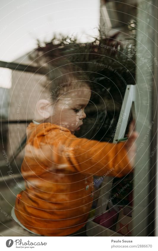 Kind durch Fenster durch Glas Isolation Quarantäne Quarantänezeit covid-19 sars-cov-2 im Innenbereich Coronavirus Prävention Pandemie Infektion Infektionsgefahr