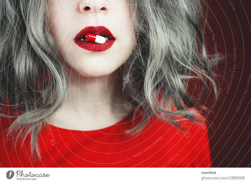 Nahaufnahme der Lippen junger Frauen, die eine Pille halten. Stil Design Haut Gesicht Lippenstift Gesundheitswesen Behandlung Rauschmittel Medikament Mensch