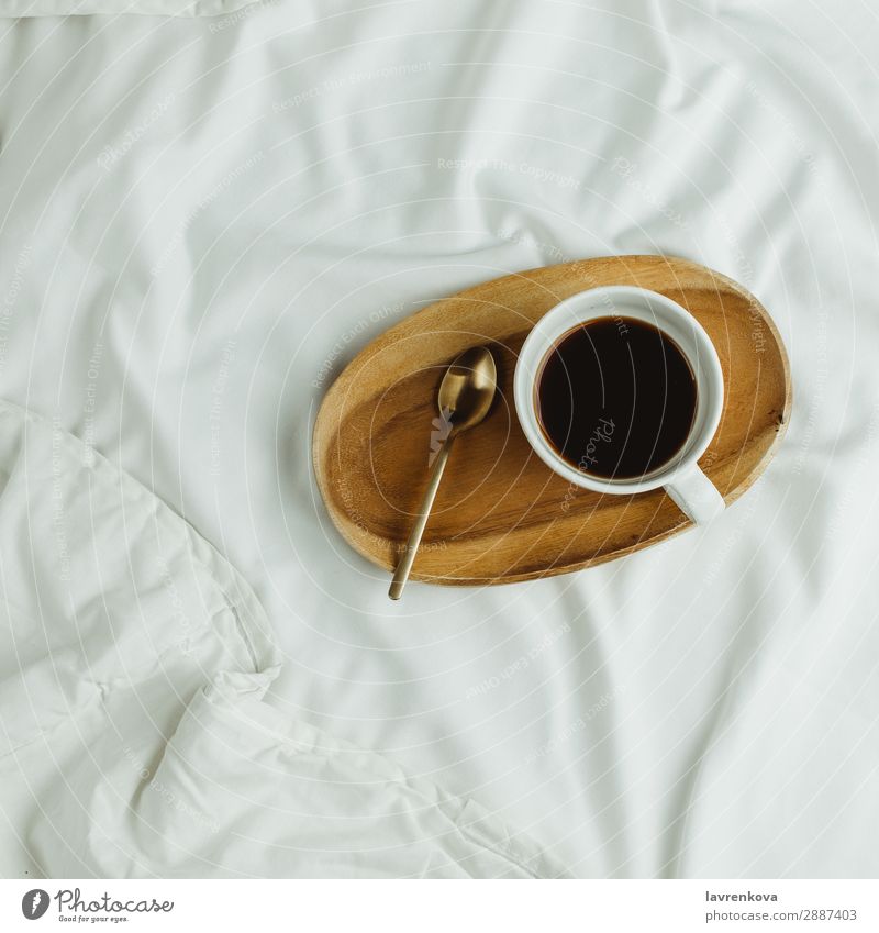 Tasse Kaffee und Löffel auf Holztablett im Bett auf weißen Laken Hintergrundbild Schlafzimmer Getränk schwarz Frühstück trinken Espresso Gesunde Ernährung