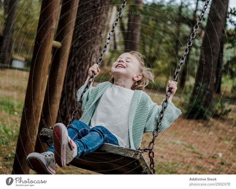 Lächelndes Mädchen auf Schaukeln im Park Wald Kind positiv Baum Natur schön Frau Kindheit Freiheit Freude Holz Lifestyle heiter Mode Garten Freizeit & Hobby