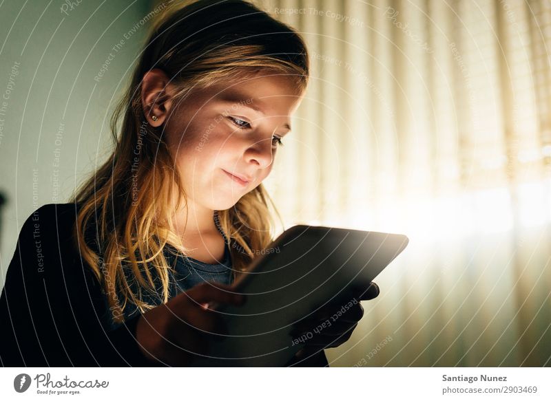Süßes blondes Mädchen, das auf einem Tablet PC spielt. Tablet Computer Kind Lächeln Spielen klein digital heimwärts Glück Etage Mensch Technik & Technologie